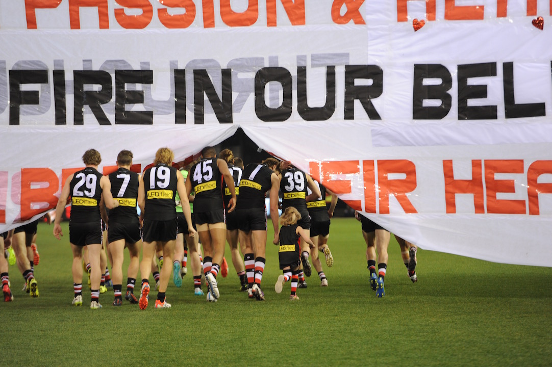 Jason Holmes (45) runs through the banner prior to his debut last weekend in Aussie rules. Photo by Kim Densham for AFANA.