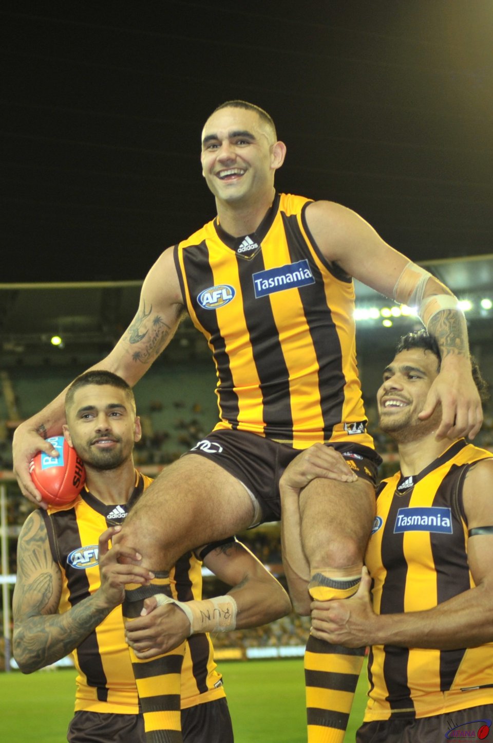 Bradley Hill and Cyril Rioli chair Shaun Burgoyne off the ground for his 300th Game
