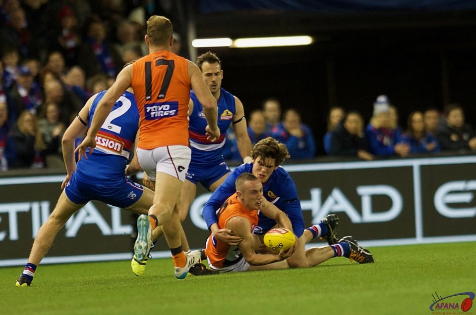 Tom Scully squeezes the handball as Lewis Young tackles