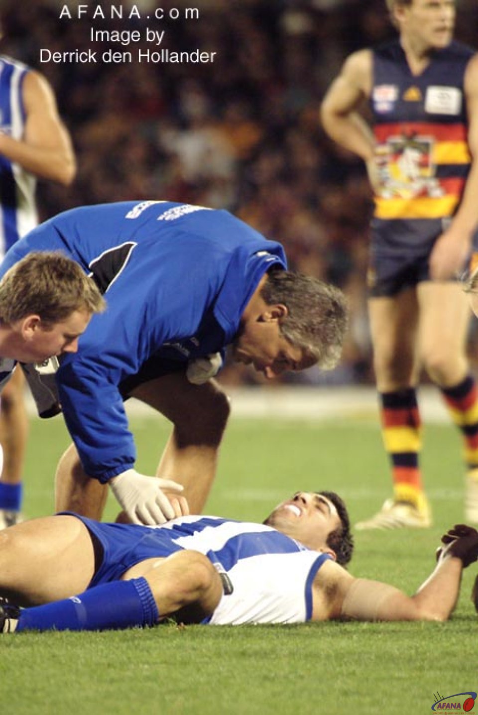 [b]An injured North Melbourne player receives assistance from Kangaroos support staff[/b]