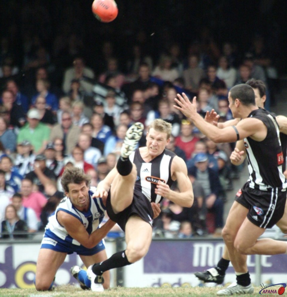 [b]Collingwood captain Nathan Buckley manages to get a kick away under huge pressure[/b]