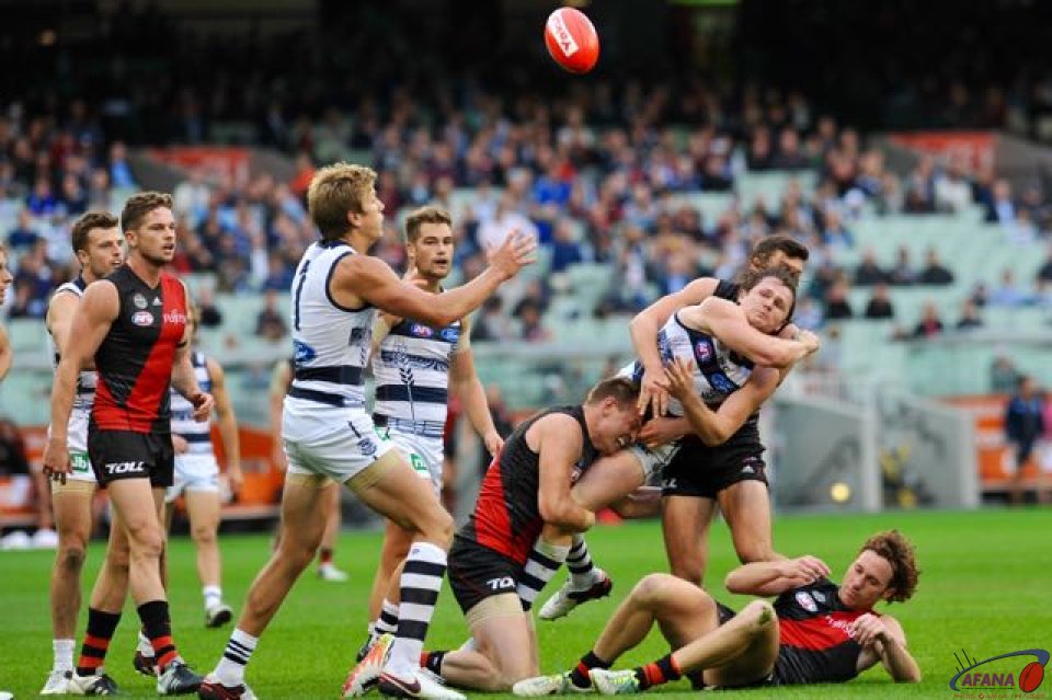 Paddy Dangerfield is tackled by Essendon Captain Brendon Goddard