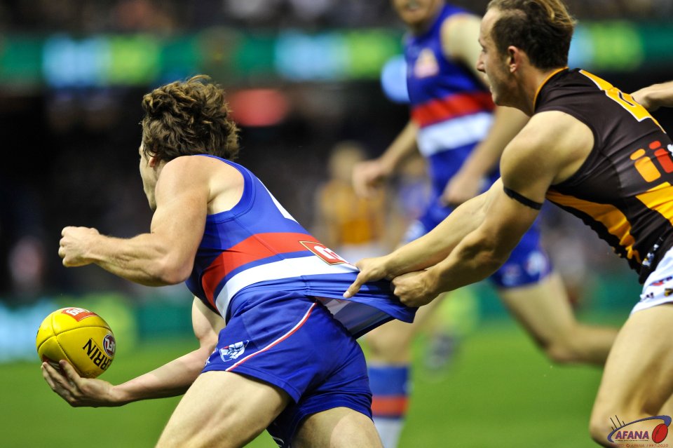 Billy Hartung hangs onto Liam Picken's jumper as the Dogs start another forward foray