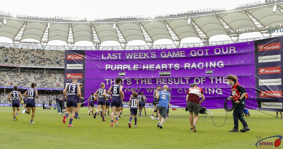 Fremantle players run through their banner