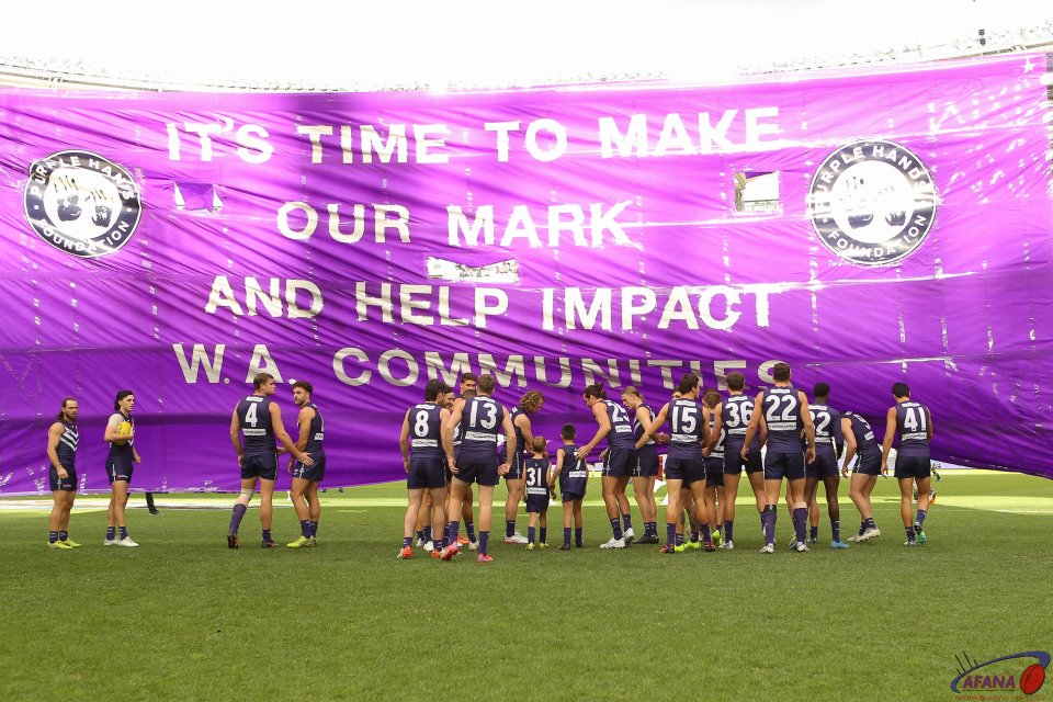 Fremantle players run through their banner